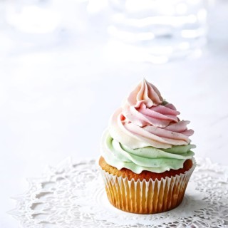 Cupcake with swirling pastel frosting on a matte grey backdrop, AI generated