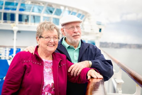 Senior adult couple enjoying the view from their passenger cruise ship railing