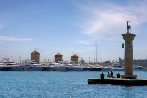 Stag Elafos, sculpture on a column, at the harbour entrance, in the background the three windmills