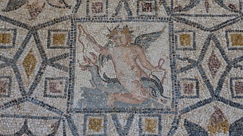 Eros riding a dolphinAncient mosaic depicting a winged man, with geometric patterns and