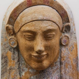 Female terracotta bust, A coloured stone relief of an ancient face with detailed facial features,