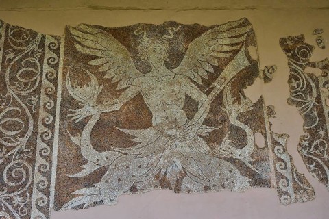 Damaged ancient mosaic with a winged mythological figure of Triton, god of the sea, and decorative