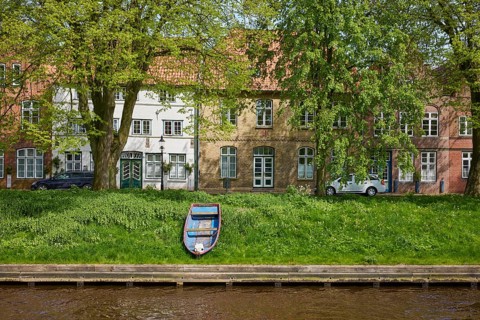 Old wooden boat and historic houses on Mittelburggraben in Friedrichstadt, North Friesland