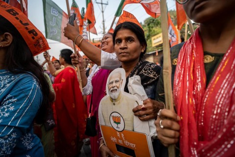 Bharatiya Janata Party (BJP) supporters holds a cutout of Narendra Modi as they arrives to to see a