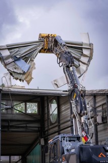 An excavator tears off the roof of a building, debris falls down, demolition, Saarbruecken,