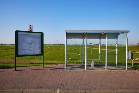 Glass bus shelter at a bus stop and information with road map in the marshland near Simonsberg,