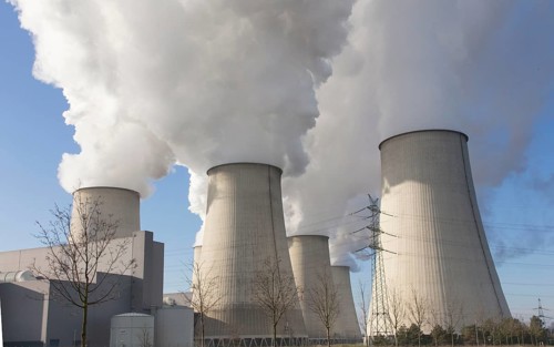 Steam rises from the cooling towers of the Vattenfall power plant in Jaenschwalde, power lines and
