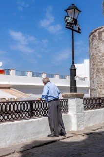 Senior citizen looking over a parapet on the street, Vejer, Andalusia, Spain, Europe