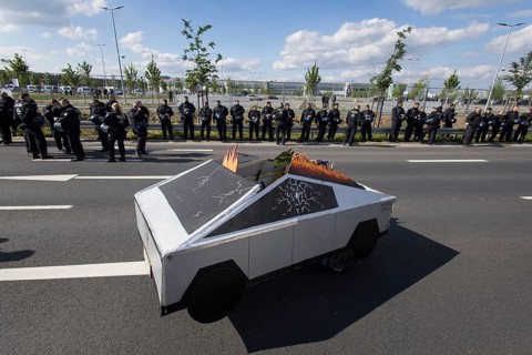 A Cybertruck cardboard model in front of the factory premises guarded by police officers during the