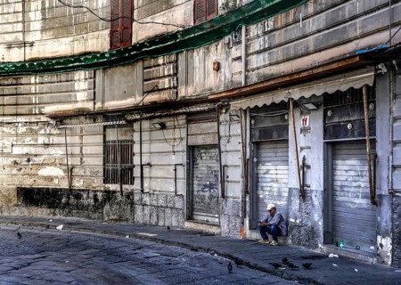 A man sits in front of a closed shop in the historic centre of Naples, 02/05/2024, Naples, Italy,