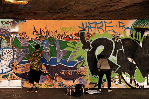 Graffiti artist at work in a skateboard park on the Thames, London, England, Great Britain