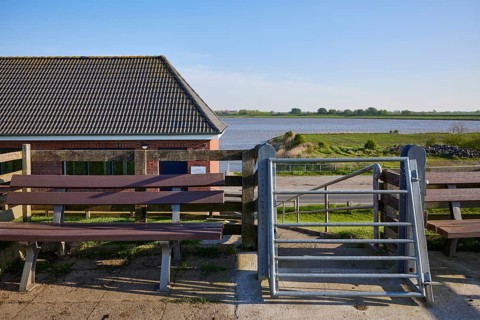 Self-closing door and bench on the dyke crest near Tetenbuell, Nordfriesland district,