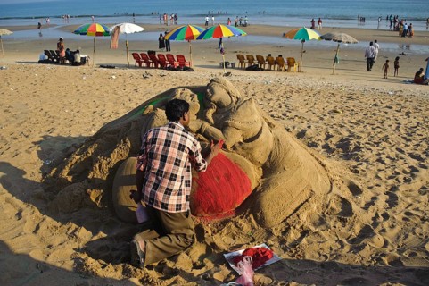 Sand artist sculpting a sand sculpture, sculpture representing a couple of lovers, beach at Puri,