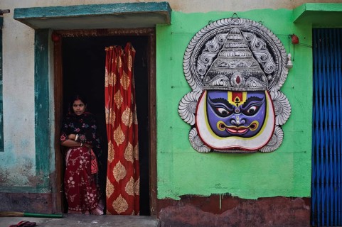 Tall mask representing a Kathakali dancer hanging on the outer wall of the house of a craftsman,