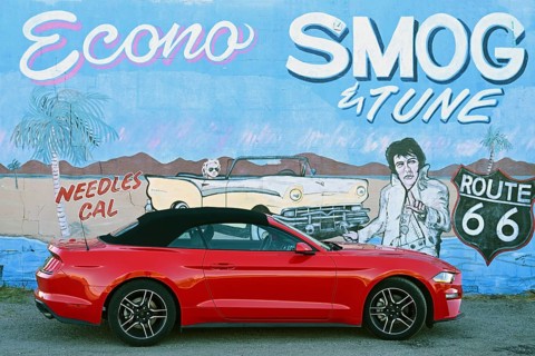 Red Ford Mustang convertible in front of mural with Elvis, Needles, California