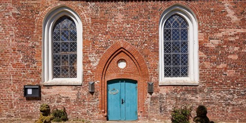 Window and entrance door to St Laurentius Church in Toenning, North Friesland district,