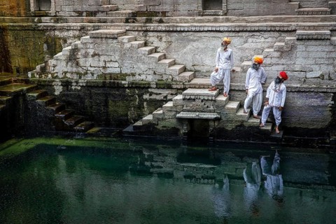 Three traditional men with turban at the steps at the stepwell Toorji Ka Jhalra in Jodhpur,