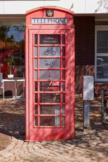 Public e-bike charging station in an old, red English telephone box on the town hall square in