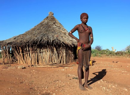 South Ethiopia, Omo region, young woman of the Hammer people standing in front of a round hut,