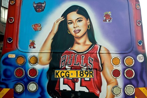 Decorated public transport called Matatu, young woman fan of the basket ball team Chicago Bulls,