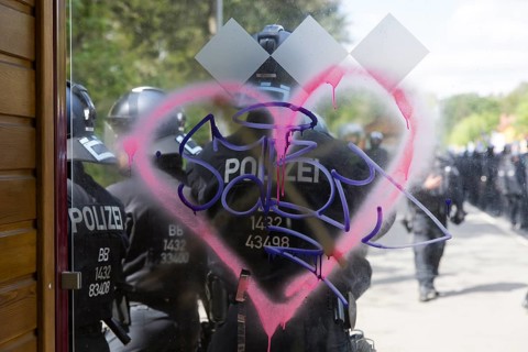 Police officers stand behind a spray-painted heart at a bus stop during the Wasser. Forest. Justice