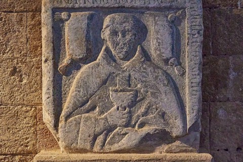 Detail of a stone relief with a drawn monk holding a book, upper part of a tomb slab, outdoor area,