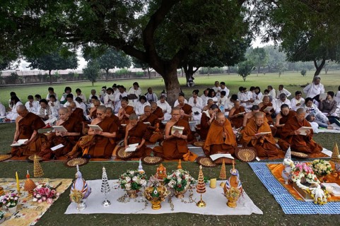 Asian tourist buddhists and nuns on pilgrimage, reading scriptures in front of the relic stupa at