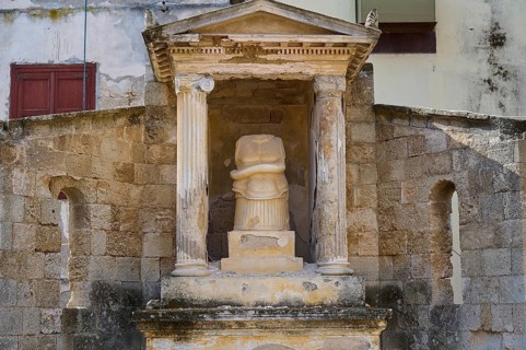 Doric columns at a historical site, temple pediment, sculpture with snake, shows signs of