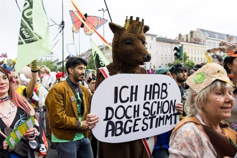 Dancer of the group 100% Tempelhofer Feld dressed as a Berlin bear with a sign Ich hab doch schon