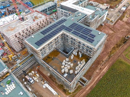 Construction site with buildings in shell construction and installed solar panels, stored building