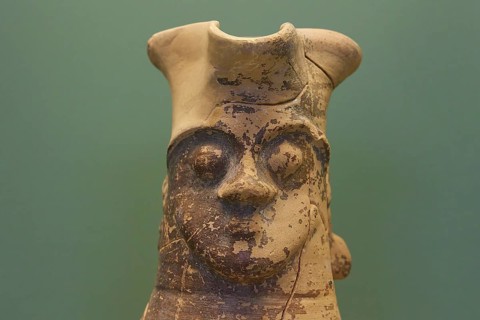 Large antique sculpture of a face with faded colours against a green background, interiors,