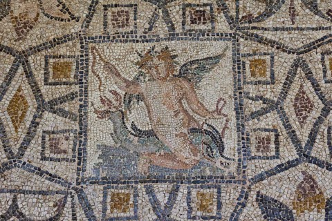 Eros riding a dolphin, Antique mosaic with a winged mythological figure in the centre, surrounded