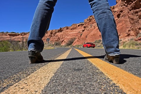 Woman standing in the middle of Route 66 looking at red Ford Mustang convertible, Dead Man's Curve,