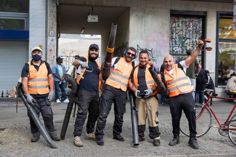 Employees of a cleaning service pose with their leaf blowers for a photo after the street parade of