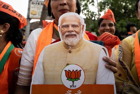 Bharatiya Janata Party (BJP) supporters holds a cutout of Narendra Modi as they arrives to to see a