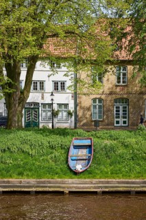 Old wooden boat and historic houses on Mittelburggraben in Friedrichstadt, North Friesland