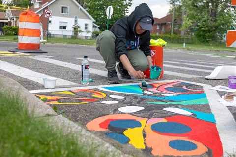 Detroit, Michigan, Artist Simone Lancaster paints a design on a city street. She is part of City