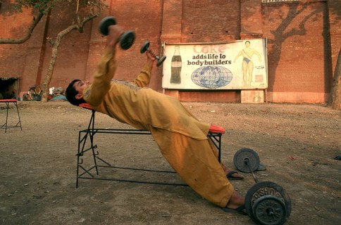 Young man lifting weights in a bodybuilding training place, Coca cola advertisement, Multan,