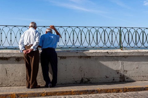 Senior citizen looking over a parapet on the street, Vejer, Andalusia, Spain, Europe