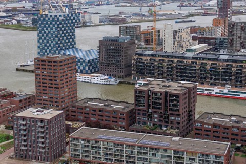Cityscape with various types of buildings along a river, near a harbour with industrial elements,