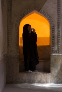 An Iranian woman in traditional dress with a chador photographed with a digital camera at the