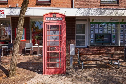 Public e-bike charging station in an old, red English telephone box on the town hall square in
