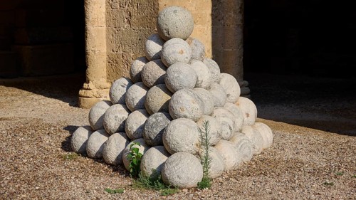 Large pyramid of stone cannonballs on a gravel floor, outdoor area, Archaeological Museum, Old