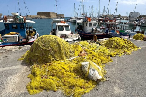 In the foreground yellow fishing nets of local Greek fishermen behind them several small fishing
