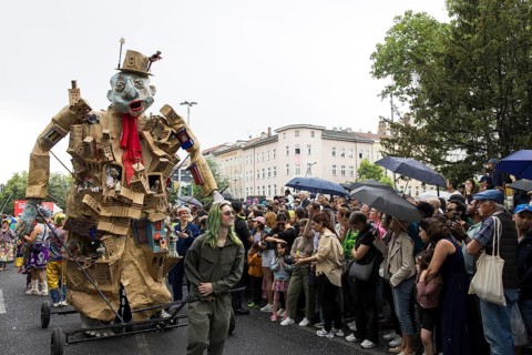 Sculpture by the Artistania group next to spectators with umbrellas at the street parade of the