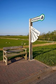 Carpooling bench and sign with fold-out destination boards in the marshland near Simonsberg,