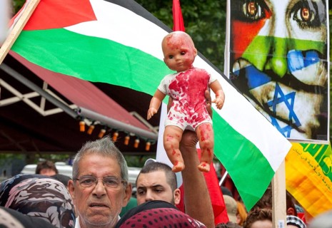 A Palestinian holds a doll coloured with red paint during the Al Quds demonstration in Berlin. Over