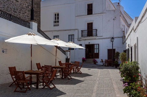 Tables and chairs of a small street cafe in the white town of Vejer in the mountains, Andalusia,