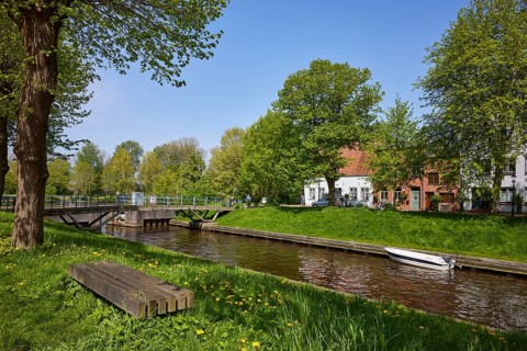 Kohbruech bridge and public wooden bench on the bank of the Mittelburggraben in Friedrichstadt,