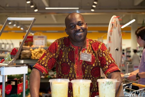 A man from Ivory Coast, black skin colour, wearing a traditional African shirt, smiling behind a